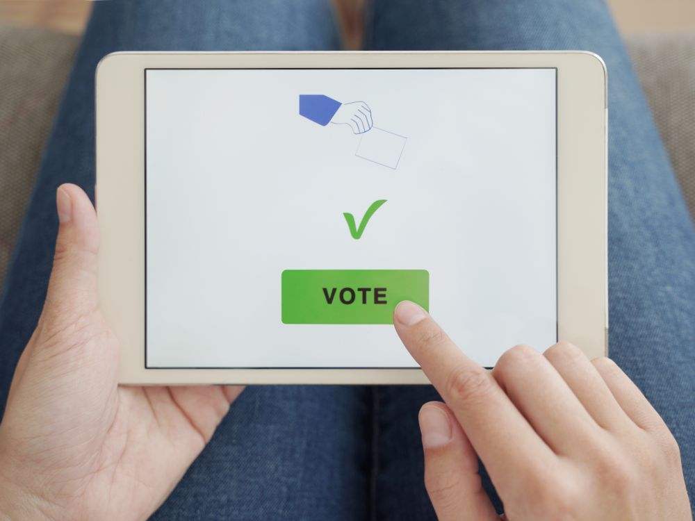 person clicking green button on tablet that says "vote"