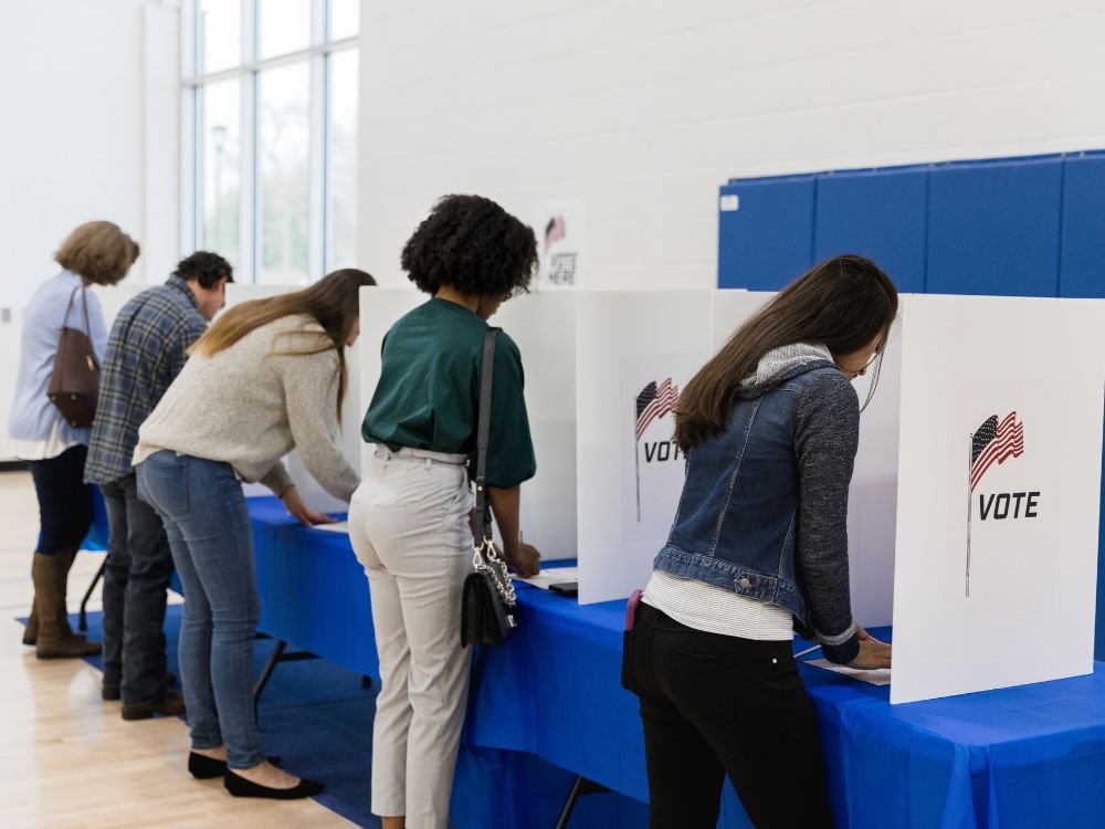 people at voting booths voting in a paper election
