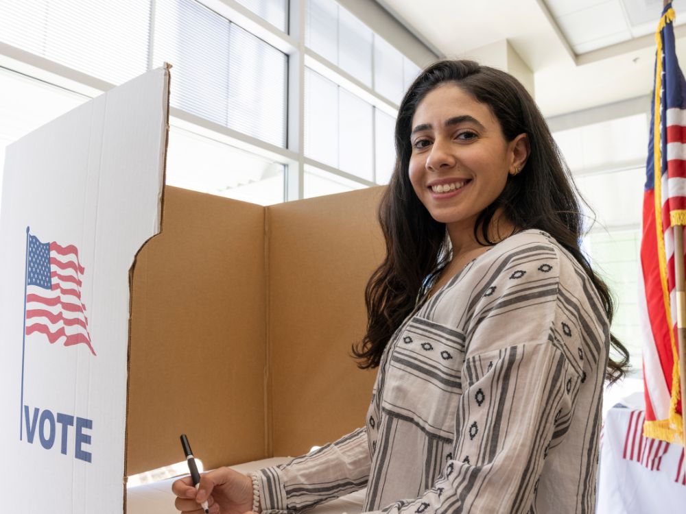 woman smiling while filling out a paper ballot