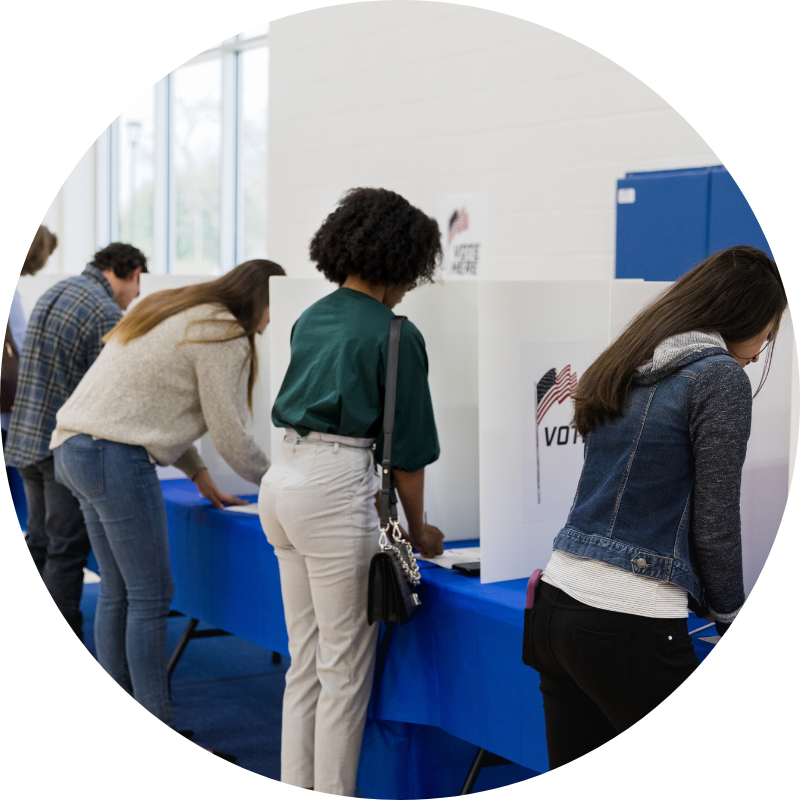 people at voting booths voting with paper ballots